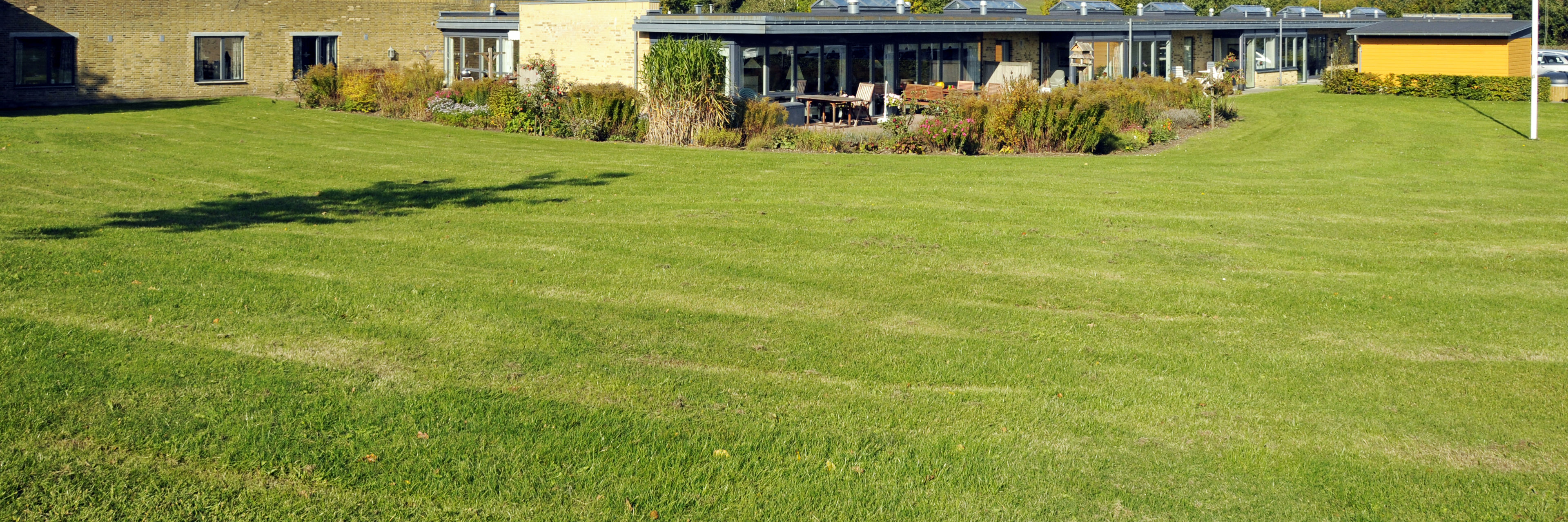 Have med græsplæne og flagstang hos Kildevang