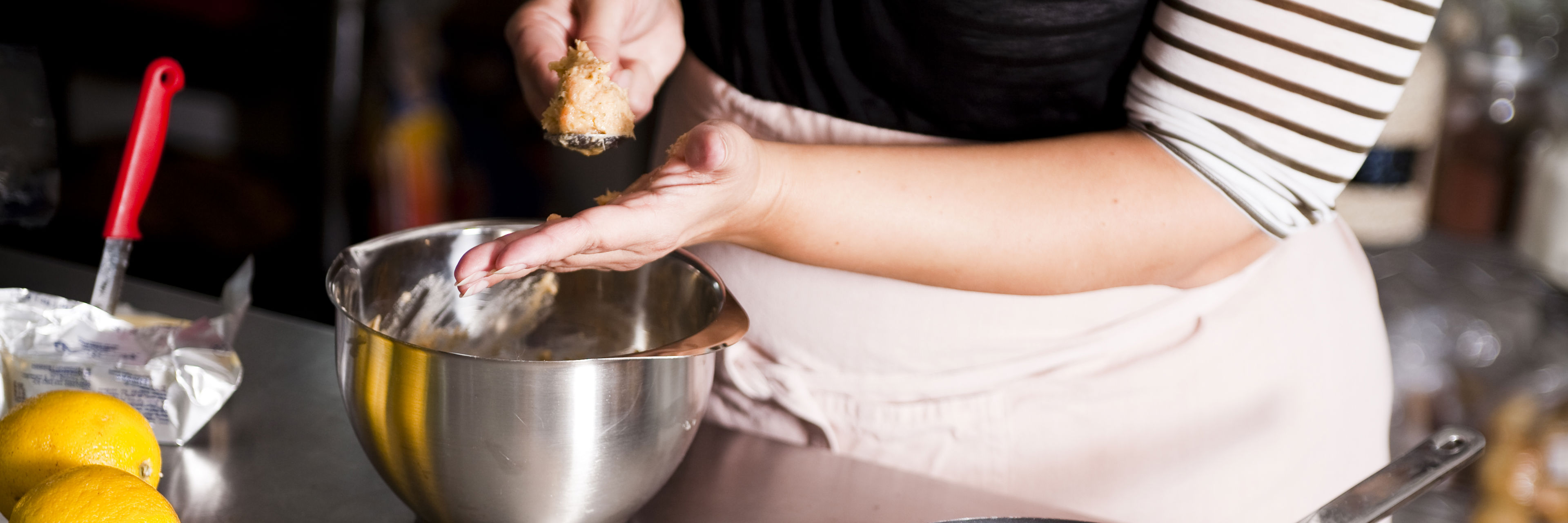 Kvinde former kødboller og steger dem på pande.