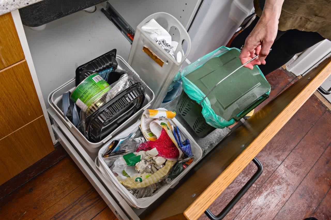 Mittens hånd løfter affaldsspand op fra skuffen