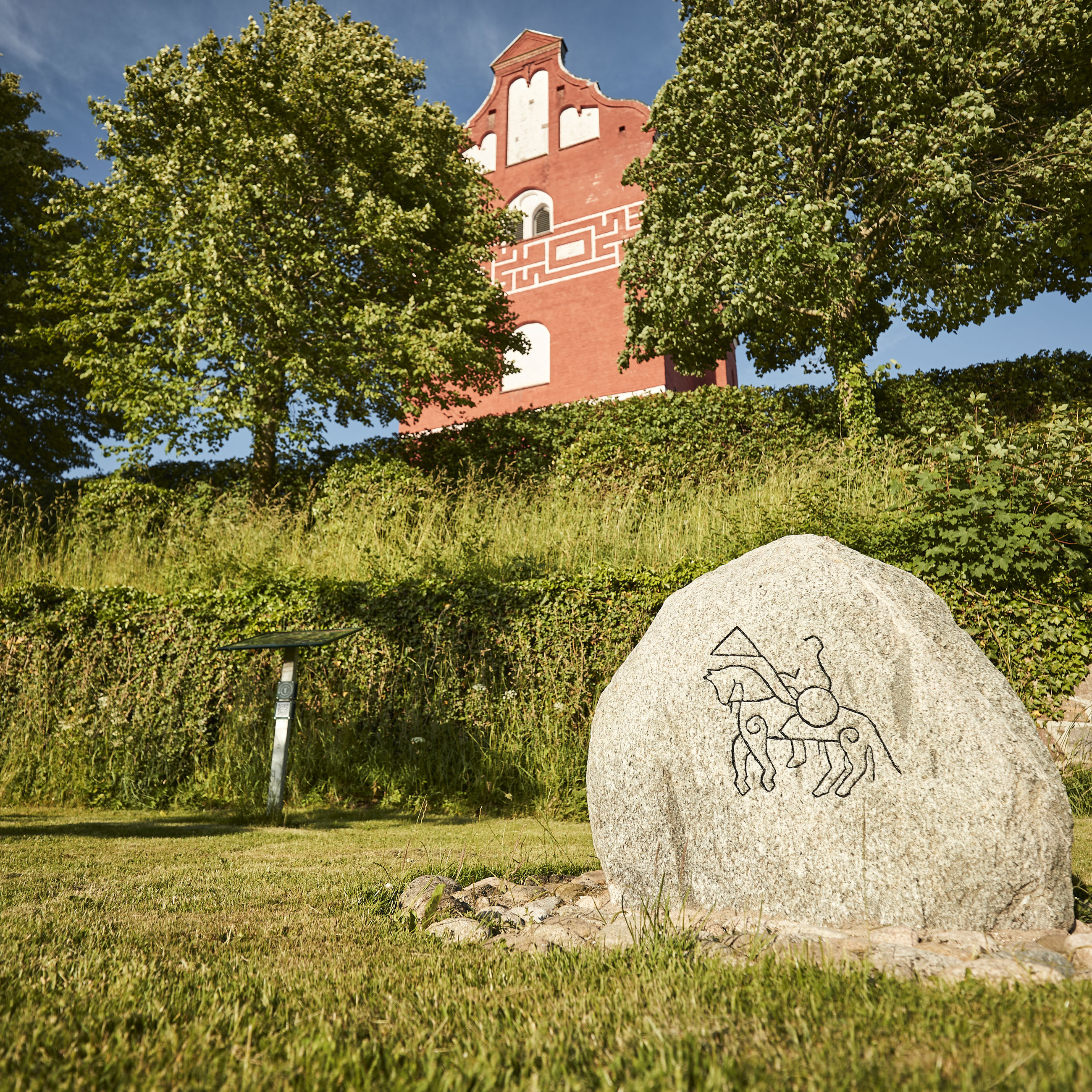 Ålum Kirke og sten med tegning af rytter på hest