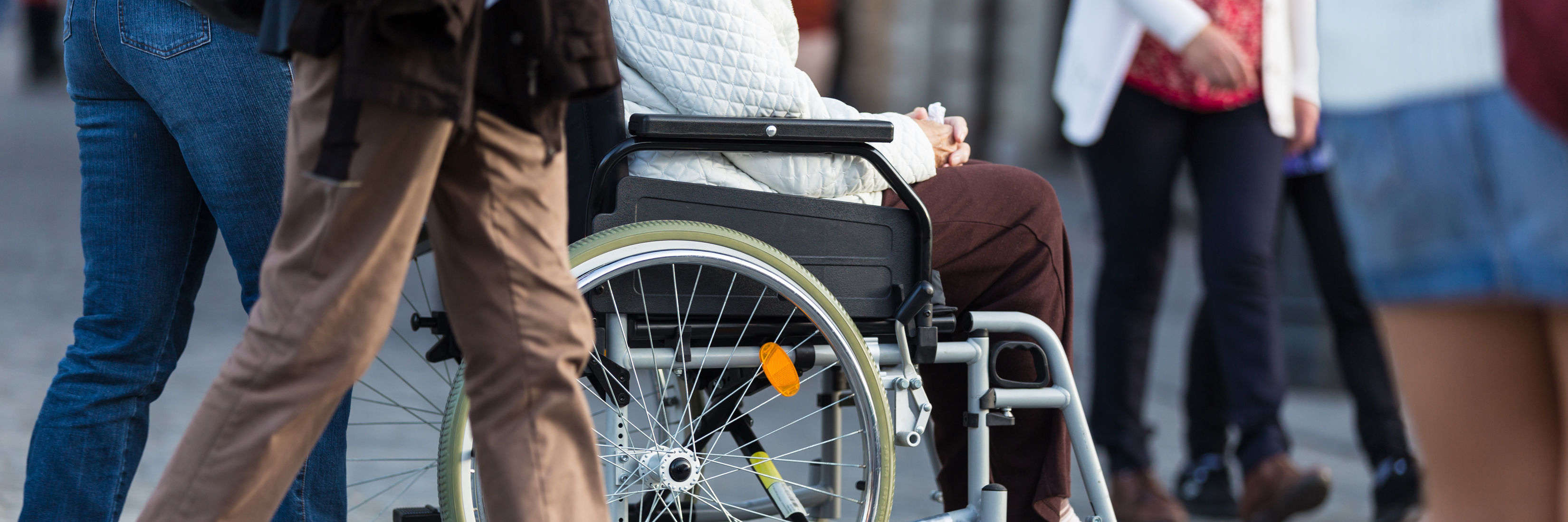 Handicappet borger i kørestol bliver ført af ledsager