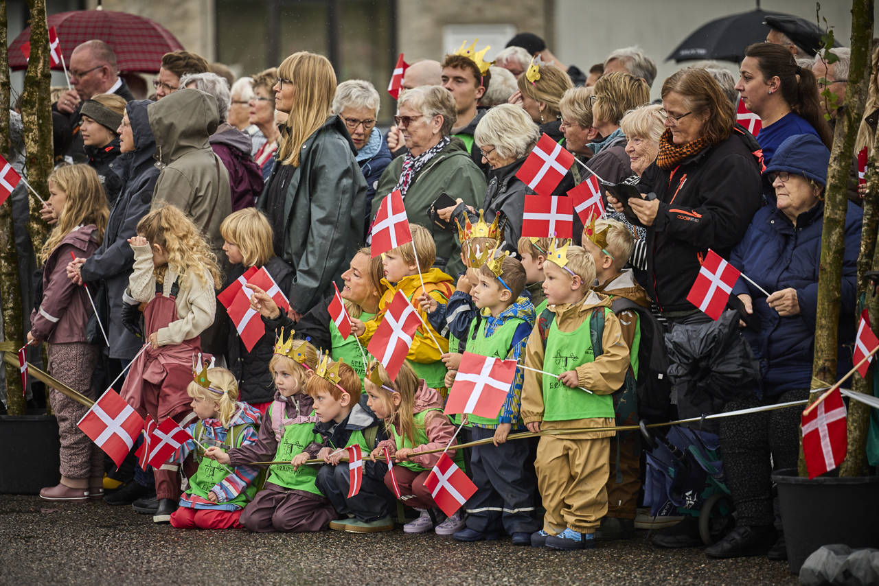 Folk står klar til at modtage Dronningen med flag på havnen