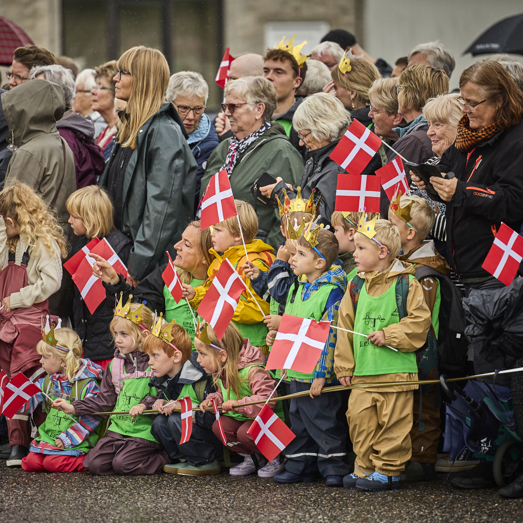 Folk står klar til at modtage Dronningen med flag på havnen