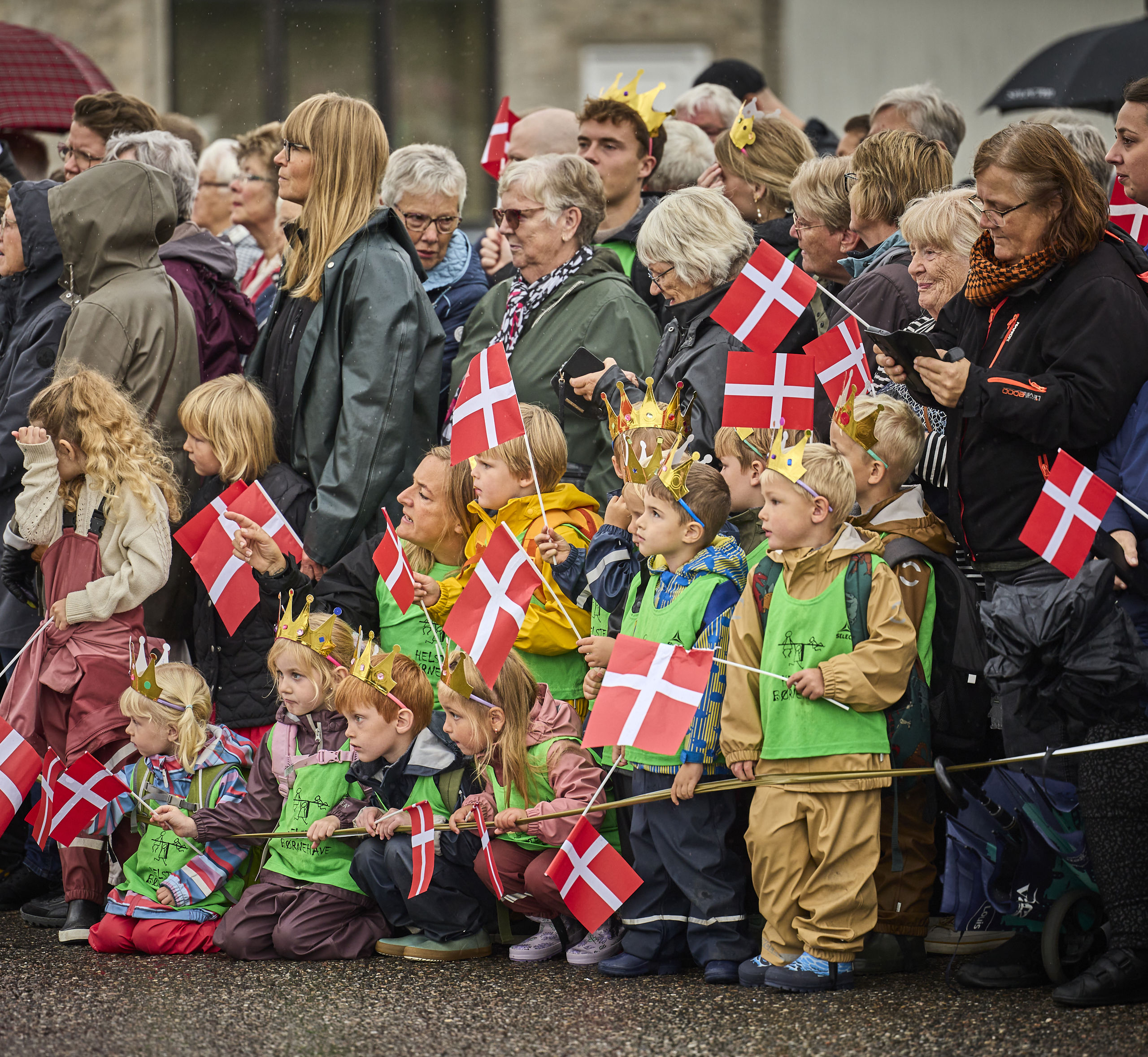 Folk står klar til at modtage Dronningen med flag på havnen